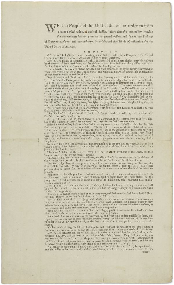 Pagina fotografata della Costituzione degli Stati Uniti con il preambolo e l'inizio dell'articolo I, con il titolo in caratteri grandi e il testo disposto su due colonne su carta invecchiata e ingiallita.