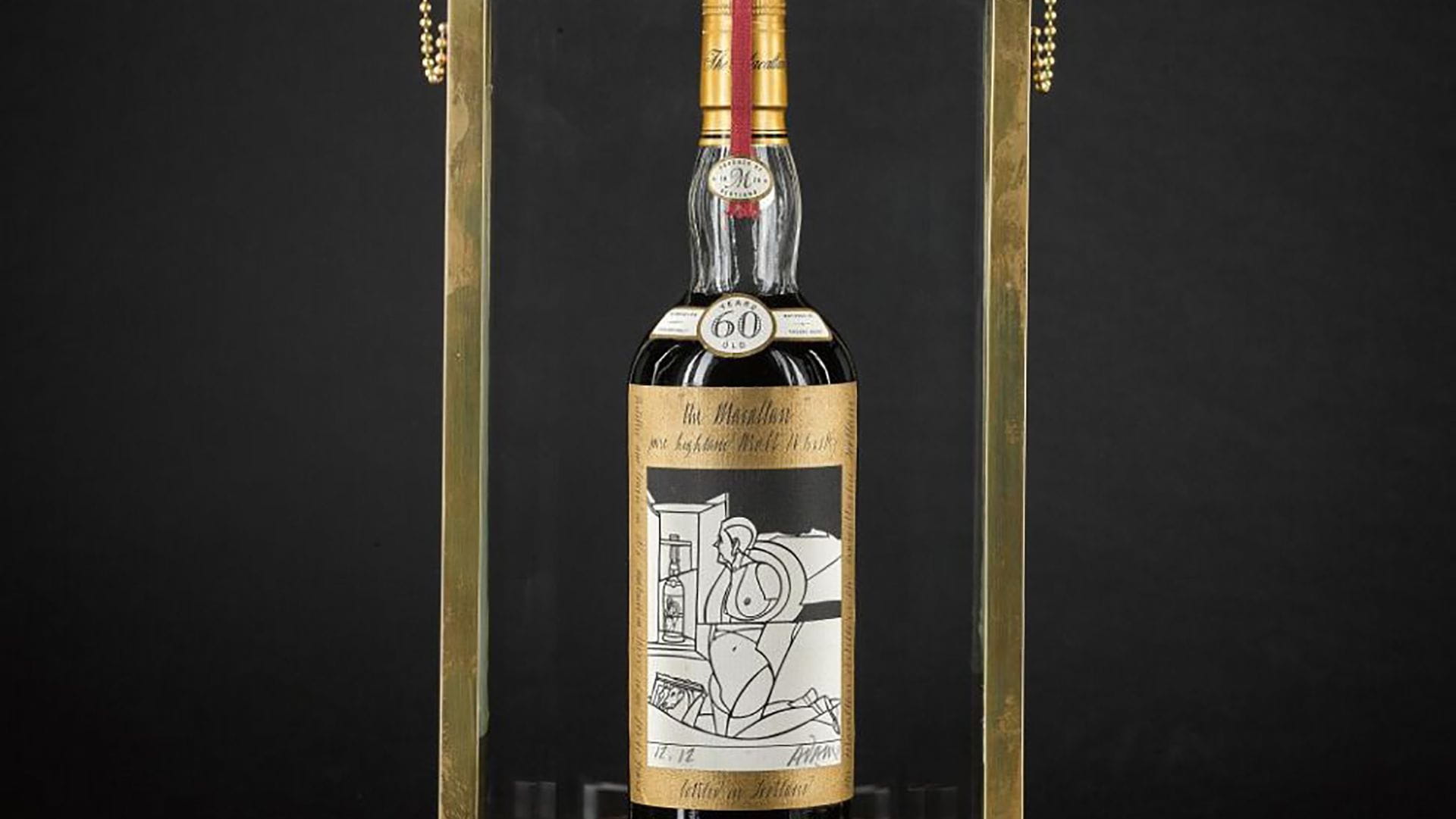 Una bottiglia di raro whisky con etichetta bianca e oro è esposta in verticale in una cornice di ottone su sfondo nero, per celebrare il suo recente record d'asta. L'etichetta presenta un'illustrazione astratta in bianco e nero.