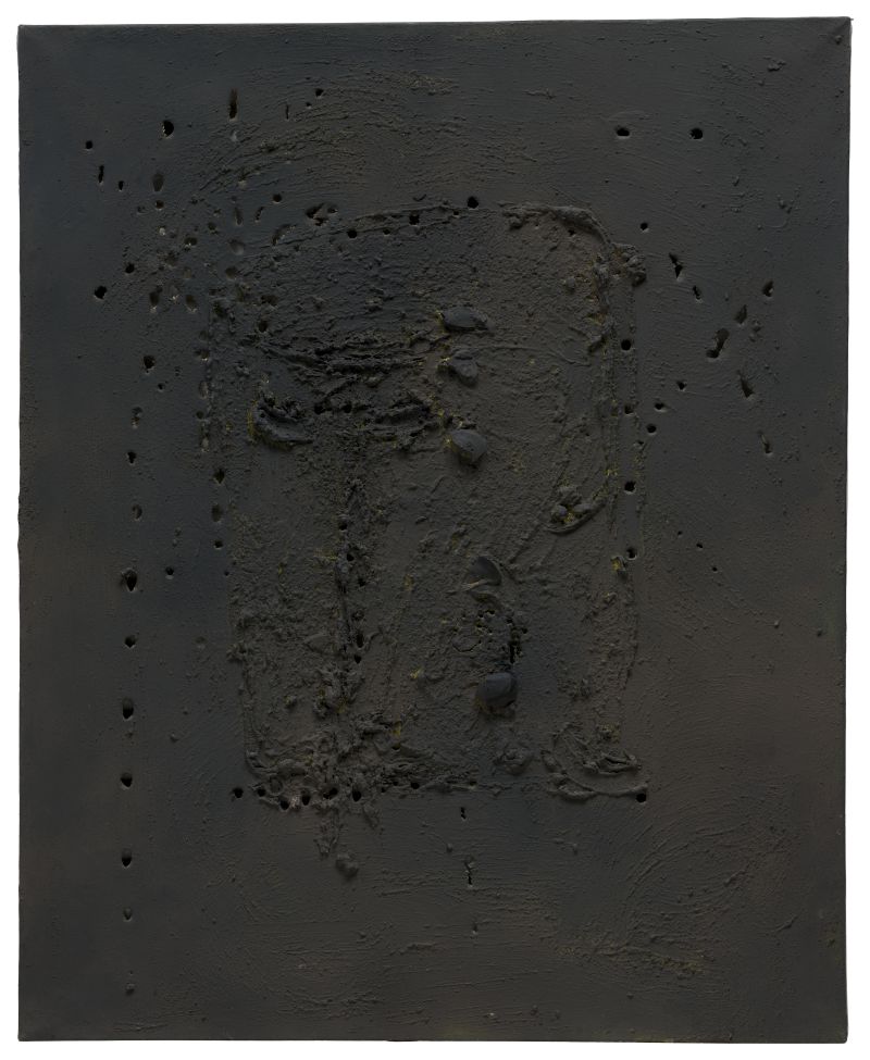 Un'opera d'arte astratta dai toni scuri, ispirata a Lucio Fontana Milano, caratterizzata da superfici ruvide e irregolari e da segni sparsi di buchi, con un'area rettangolare in rilievo al centro, il tutto dipinto nei toni del nero e del grigio intenso.