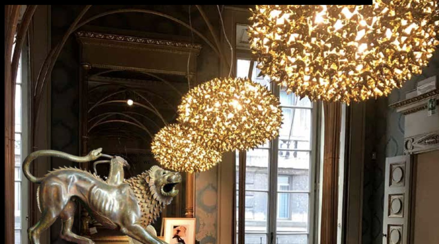 Interni lussuosi con grandi lampadari ornati, una scultura di leone metallico e alti specchi che riflettono la stanza, evocando la grandezza dei musei d'impresa. Una finestra mostra un edificio classico all'esterno, mentre la luce calda riempie lo spazio elegante.